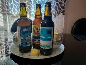 three bottles of beer sitting on a plate at Leśny zakątek in Rękusy