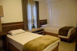 a hotel room with two beds and a window at Suítes Trindade in Florianópolis