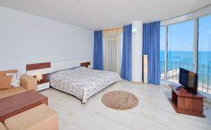 a bedroom with a bed and a television and a balcony at Family Hotel Regata in Pomorie