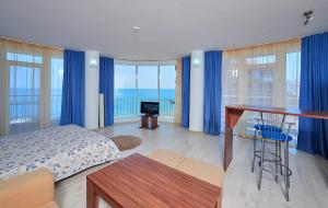 a bedroom with a bed and a desk with blue curtains at Family Hotel Regata in Pomorie
