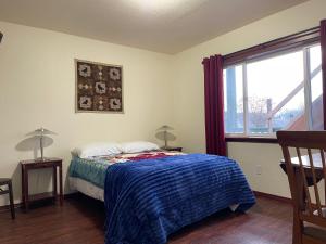 HoonahAlaskanorthwindinn的一间卧室配有一张带蓝色毯子的床和窗户。