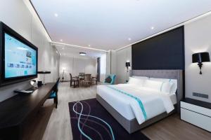 a bedroom with a large bed and a flat screen tv at Xana Hotelle Luzhou High-Speed Railway Station Trading Market Passenger Terminal in Luzhou