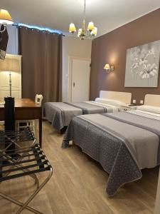um quarto de hotel com três camas e uma mesa em Hotel Azur em Lyon mais 50 fotografias