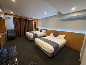 a hotel room with two beds and a chair at Goodview Hotel in Auckland