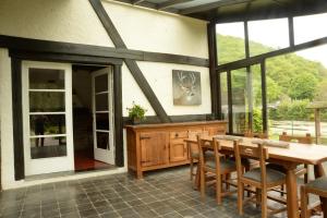 een eetkamer met een tafel, stoelen en ramen bij Gîte la Semois à Mouzaive Vresse sur Semois in Vresse-sur-Semois