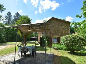 a table under a pavilion in front of a house at Cosy holiday home with garden in Villefranche-du-Périgord