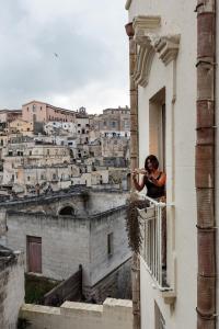 a woman standing on a balcony looking out of a building at Alla dimora di Chiara Suite and Rooms in Matera