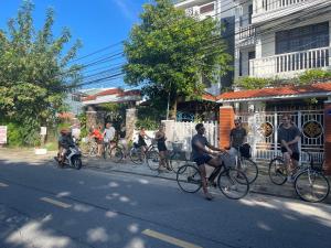 a group of people riding bikes down a street at Cheerful Hoi An Hostel in Hoi An
