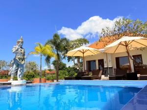 a swimming pool with a statue in front of a house at Pooja Ocean View Cottage in Nusa Penida