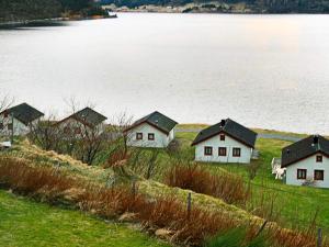 a group of houses in a field next to a body of water at 7 person holiday home in Selje-By Traum in Selje
