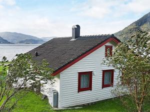 a white house with red windows next to a body of water at 7 person holiday home in Selje-By Traum in Selje