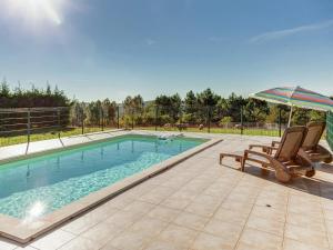 a swimming pool with two chairs and an umbrella at Dordogne Family Haven in Orliac