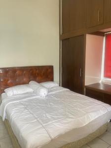 a large bed with white sheets and a wooden headboard at Kota bunga in Cikundul