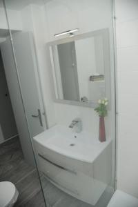 a white bathroom with a sink and a mirror at L'Azur Promenade in Nice