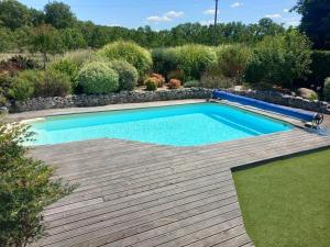a swimming pool in a garden with a wooden deck at Maison spacieuse Périgord Pourpre avec piscine partagée - FR-1-616-498 in Monsaguel