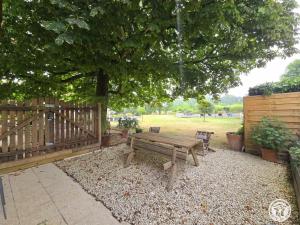 a wooden bench sitting under a tree next to a fence at Maison spacieuse Périgord Pourpre avec piscine partagée - FR-1-616-498 in Monsaguel