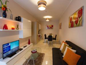 - un salon avec un canapé noir et une télévision dans l'établissement Belle Apartments, à San Ġiljan