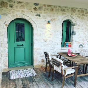 a green door on a stone building with a table and chairs at Bellou Villas Sivota in Syvota
