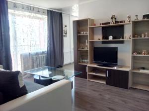 a living room with a tv and a glass table at L.E.C. Travel Apartments Ventspils in Ventspils