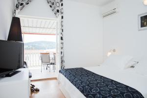 a bedroom with a bed and a television and a balcony at Hana Home - Apartments Tisno in Tisno