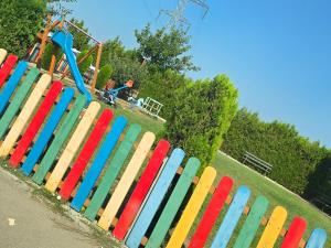 a colorful fence in a park with a roller coaster at Coquette Appart in Eforie