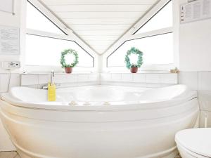 a white bathroom with a tub and two windows at 10 person holiday home in Thisted-By Traum in Klitmøller
