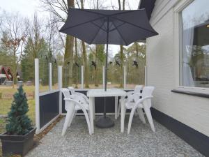 a table and chairs with an umbrella on a patio at Holiday Home in Stramproy near Nature Reserves in Stramproy
