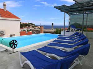 a group of blue lounge chairs next to a swimming pool at Holiday Home in Korcula with Sea View in Zavalatica