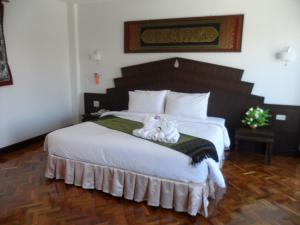 Un dormitorio con una cama grande con dos gatos. en Baiyoke Chalet Hotel en Mae Hong Son