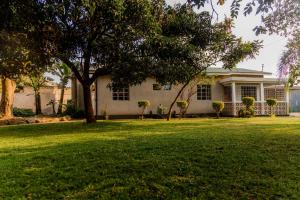 a white house with a tree in a yard at Arusha backpackers homes in Arusha