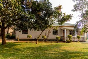 a white house with trees in front of it at Arusha backpackers homes in Arusha +18 photos