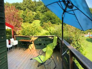 a deck with a table and chairs and an umbrella at Vintage chalet in a very beautiful landscape in Aywaille