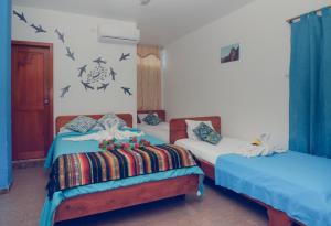 two beds in a room with birds on the wall at Costa Del Sol in Puerto Ayora