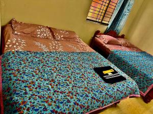a bed with a comforter with a book on it at Anna Miracle Homestay in Kāsarkod +21 photos