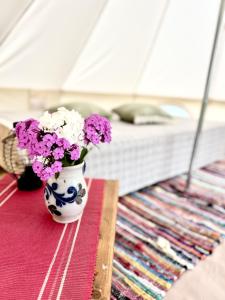 a vase filled with purple and white flowers on a table at Ploomi Glämping in Tiilike