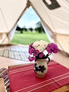 a vase filled with purple and white flowers on a table at Ploomi Glämping in Tiilike +5 photos