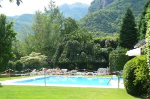 a swimming pool with people sitting in chairs next to a mountain at Hotel Aurora in Chiavenna