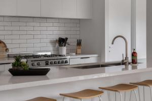 a white kitchen with a stove and a sink at Luxury On Lakeside in Mount Beauty