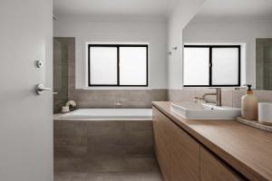 a bathroom with a tub and a sink and two windows at Luxury On Lakeside in Mount Beauty +13 photos