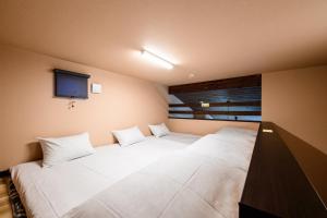 a bedroom with two white beds and a television at Hana-No-Mizuumi Hotel in Hakone