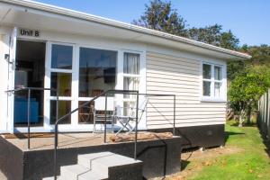 a small white house with a porch and stairs at Waitangi Beach Unit B in Paihia