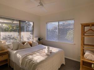 Un dormitorio con una cama grande y dos ventanas. en Eagle Bay Summerhaus, en Dunsborough