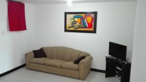 uma sala de estar com um sofá e uma pintura na parede em Playa Los Cocos em Santa Marta