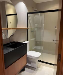 a bathroom with a toilet and a glass shower at Beira mar porto de pedras essence C101 in Pôrto de Pedras