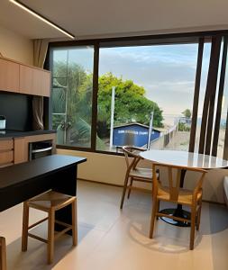 a kitchen with a table and chairs and a large window at Beira mar porto de pedras essence C101 in Pôrto de Pedras