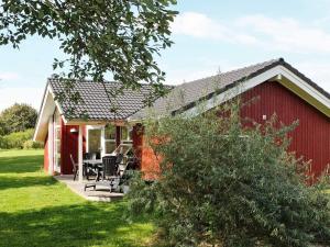 eine rote Scheune mit einem Tisch und Stühlen davor in der Unterkunft Holiday home in Großenbrode with bubble bath in Großenbrode