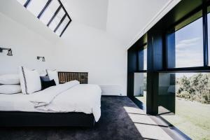 a bedroom with a large bed and large windows at Alkina Lodge Mira in Wattle Hill