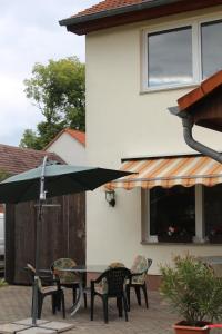 un tavolo con sedie e un ombrellone di fronte a una casa di Kleines Schmuckstück a Ermstedt