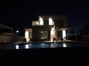 a house with a swimming pool at night at Villa Cape Vergoti in Lozenets +14 photos