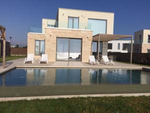 a house with a swimming pool and two lawn chairs at Villa Cape Vergoti in Lozenets